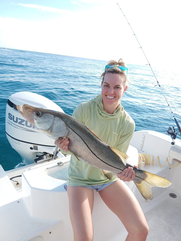 a girl holding a snook on a boat in new smyrna beach, fl