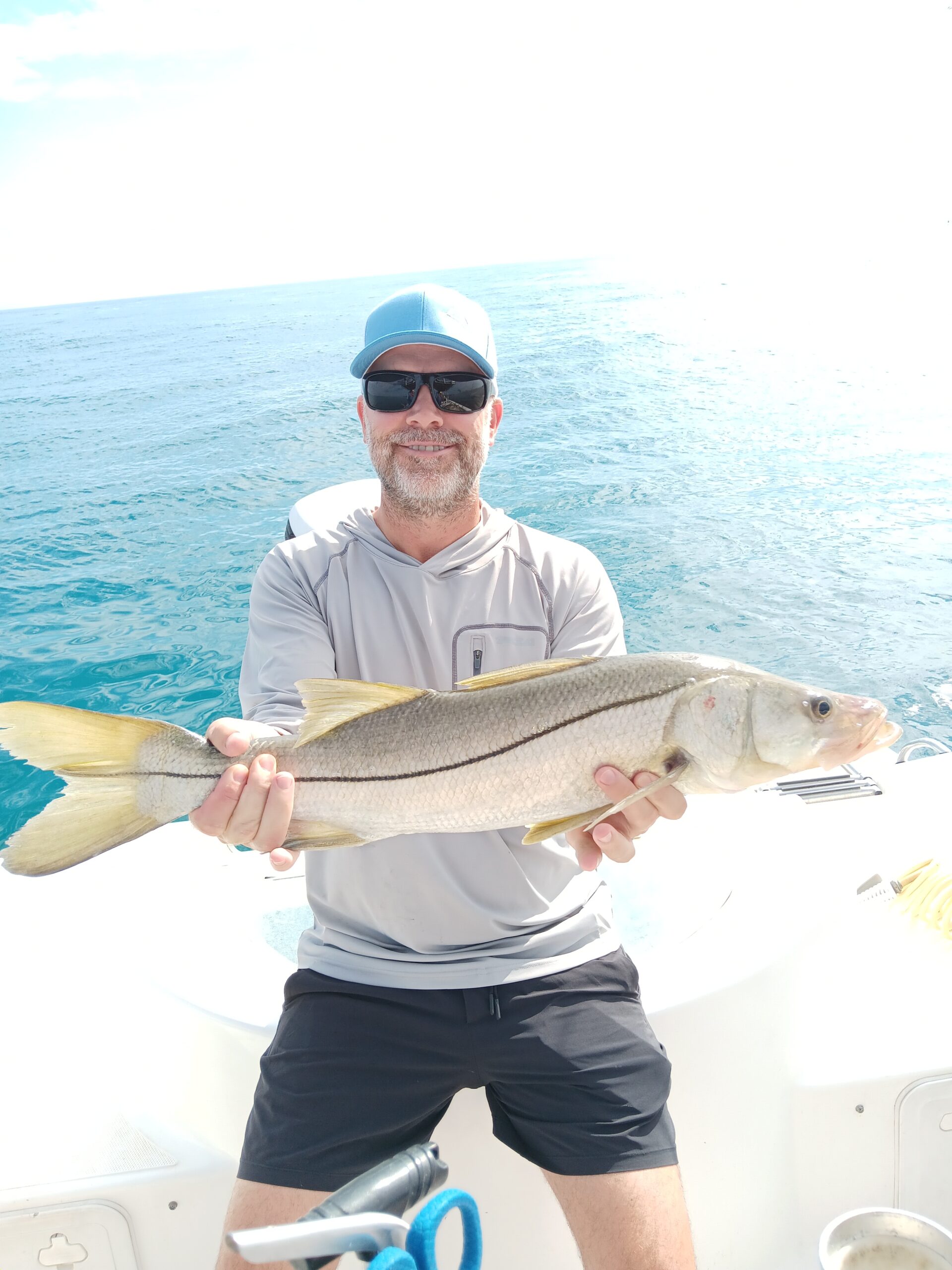 a guy holding a snook on a boat in new smyrna beach fl