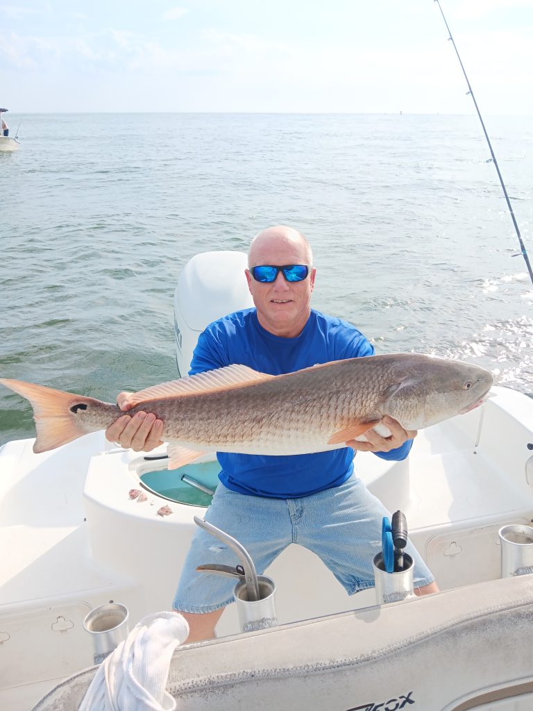 a guy holding a redfish on a boat in new smyrna beach, fl