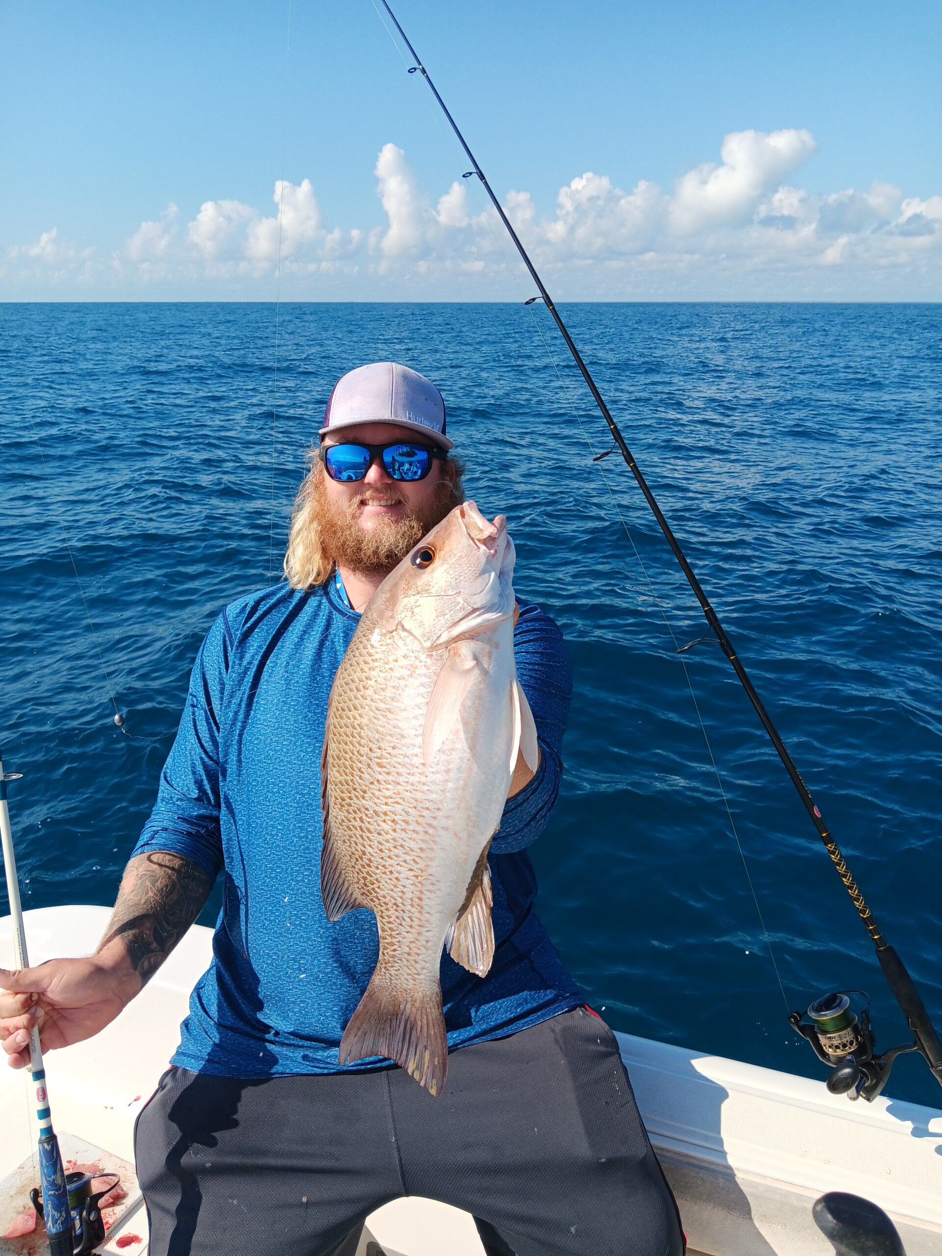 a guy holding a red fish on a boat in new smyrna beach fl