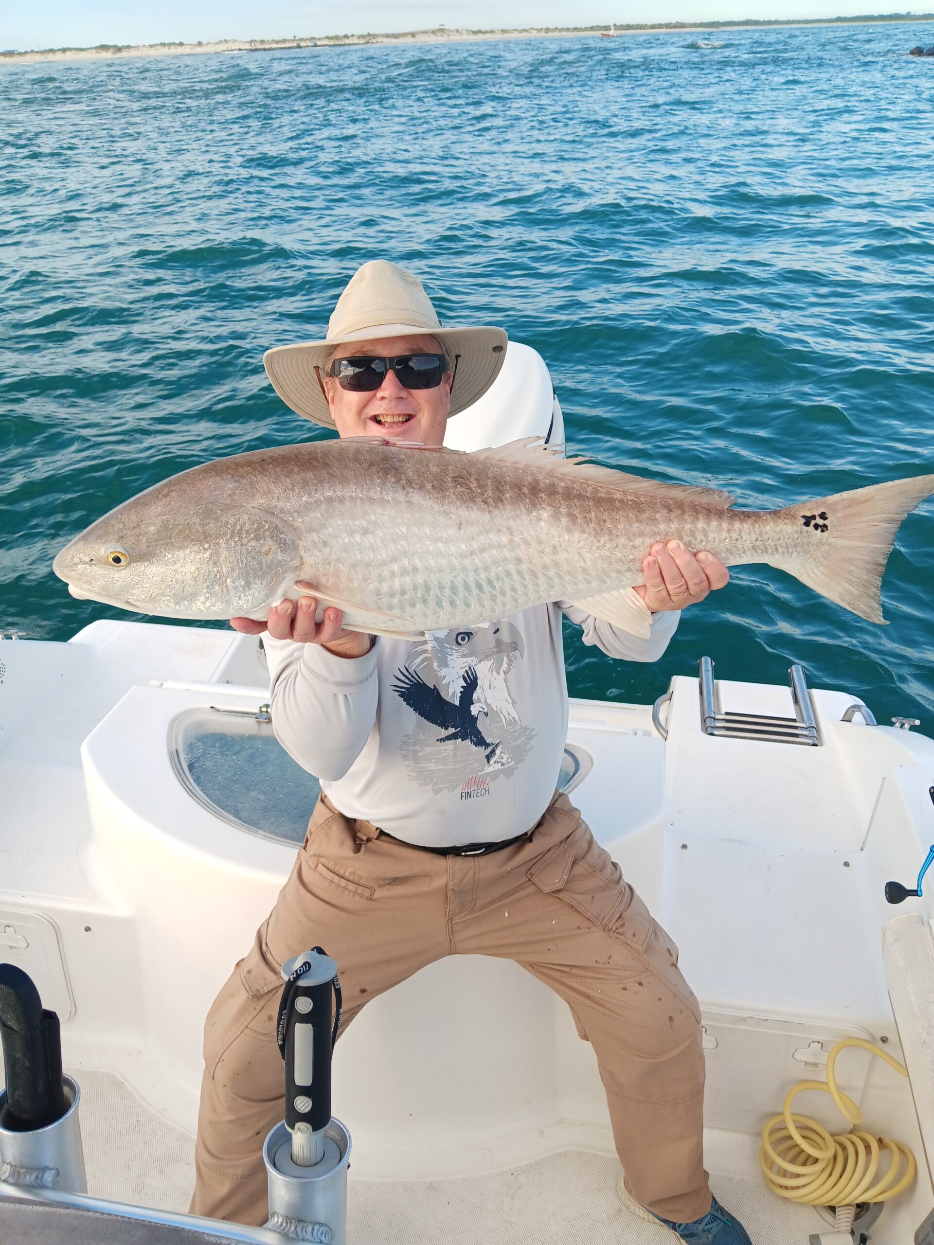 a guy holding a red fish on a boat in new smyrna beach fl