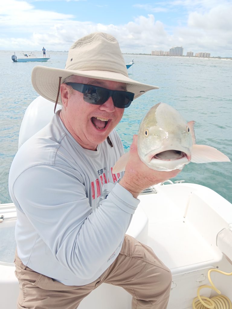 a guy holding a redfish on a boat in new smyrna beach, fl