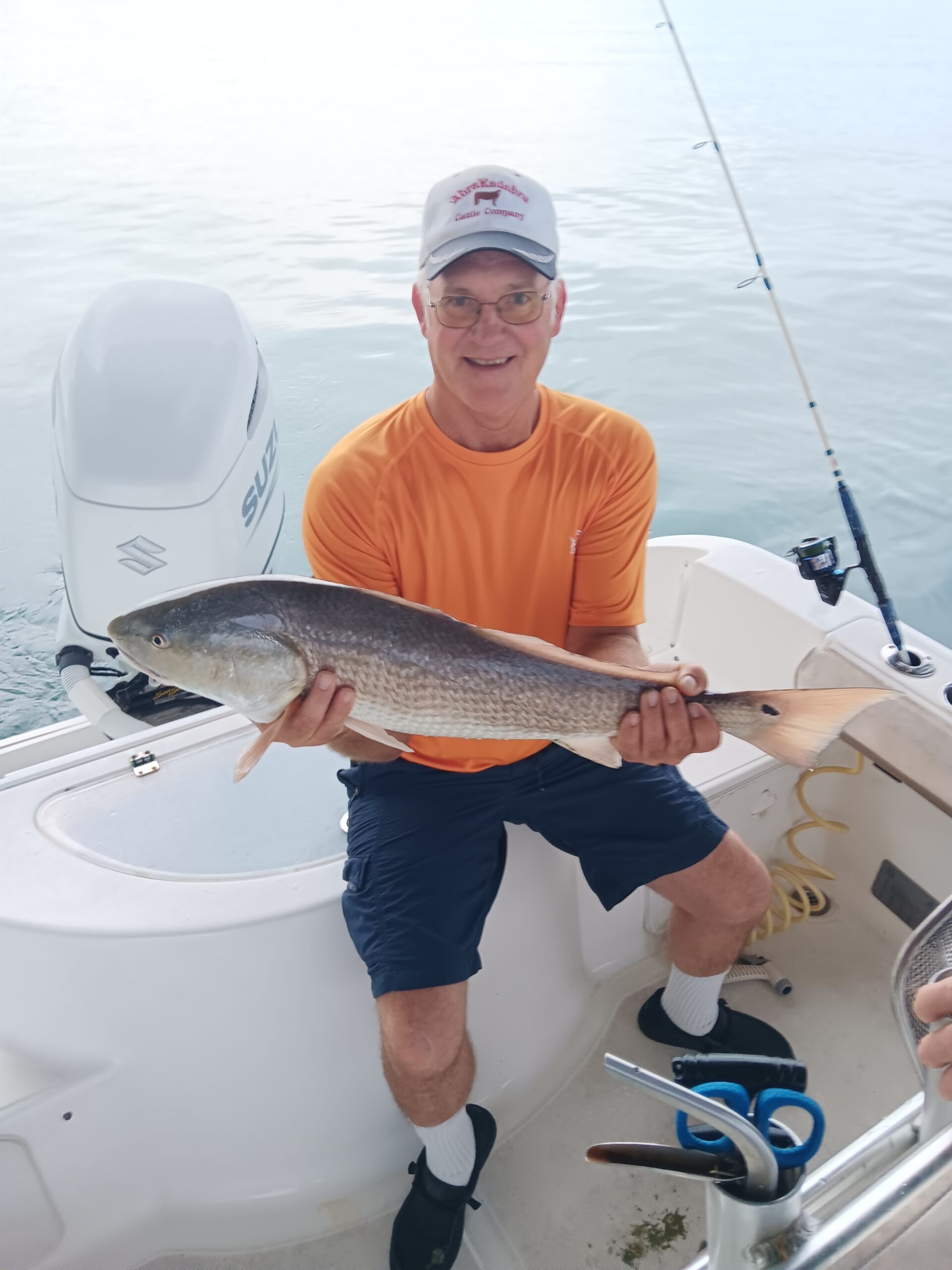 a guy holding a red fish on a boat in new smyrna beach fl