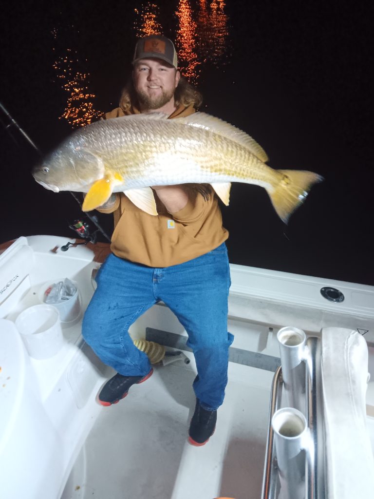 a guy holding a redfish on a boat in new smyrna beach, fl