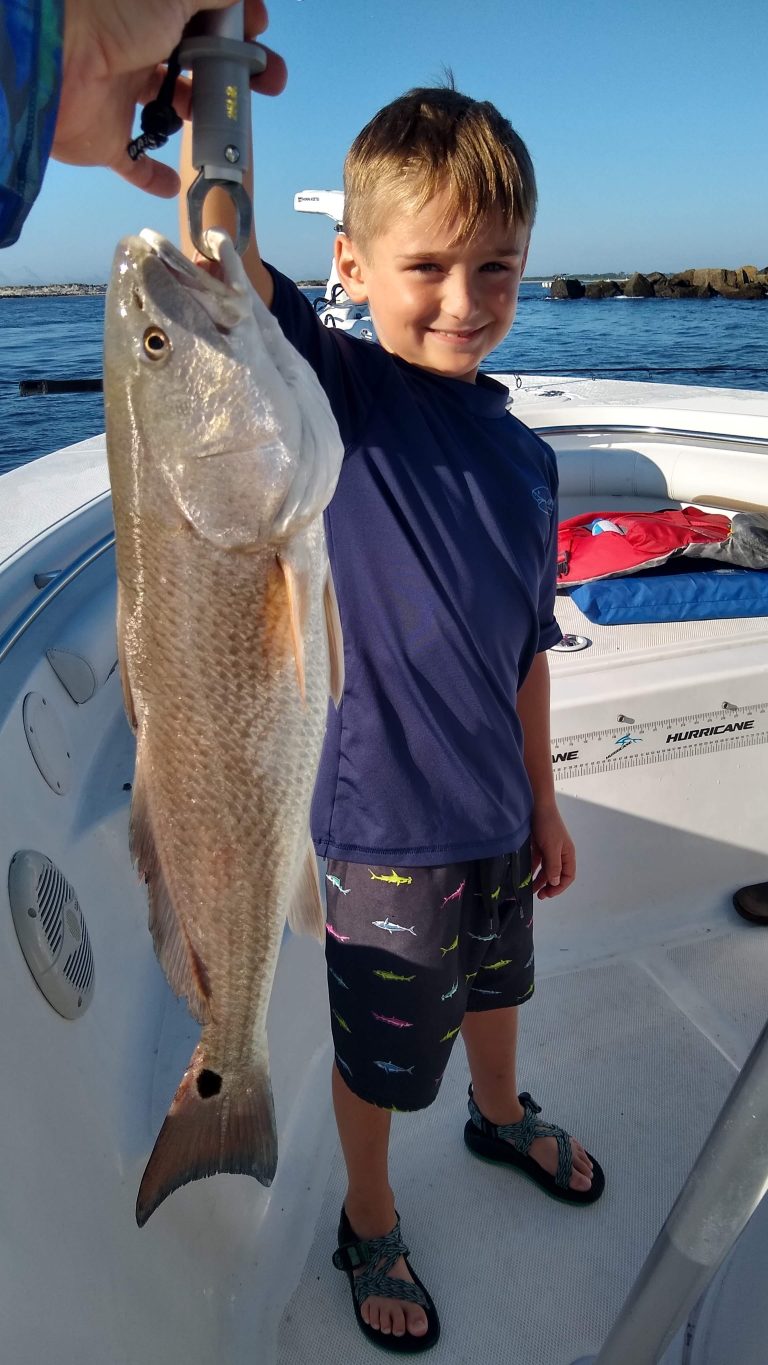 a little boy holding a redfish on a boat in new smyrna beach, fl