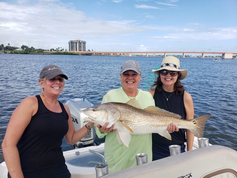 three ladies holding a redfish on a boat in new smyrna beach, fl