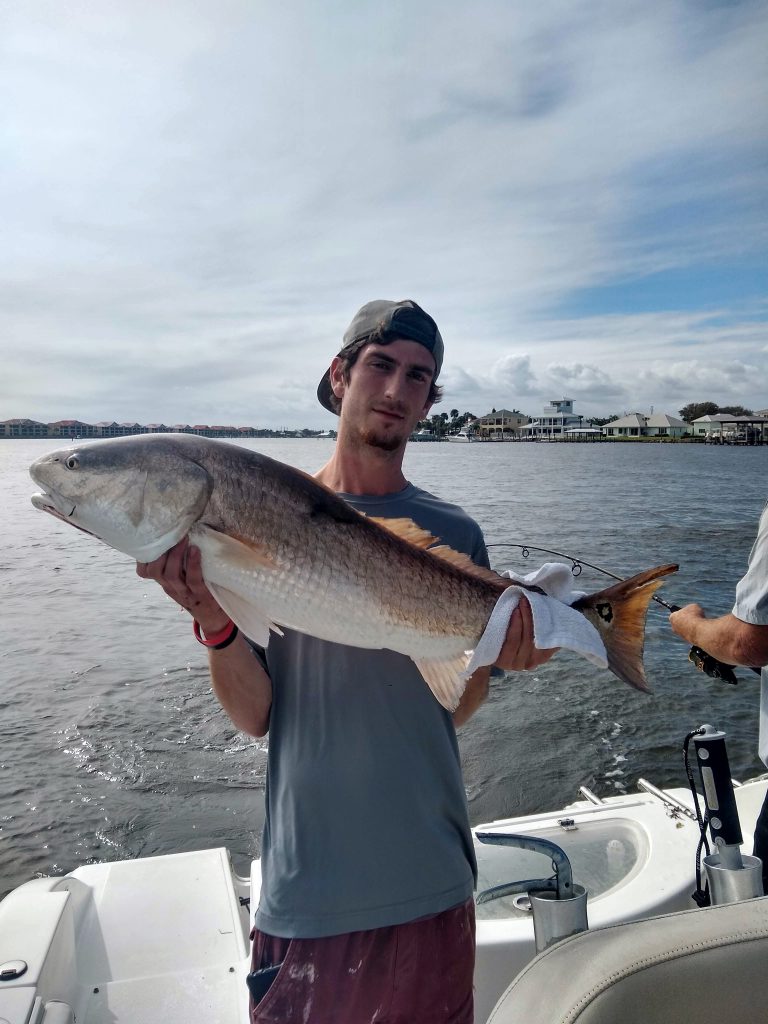 a guy holding a redfish on a boat in new smyrna beach, fl