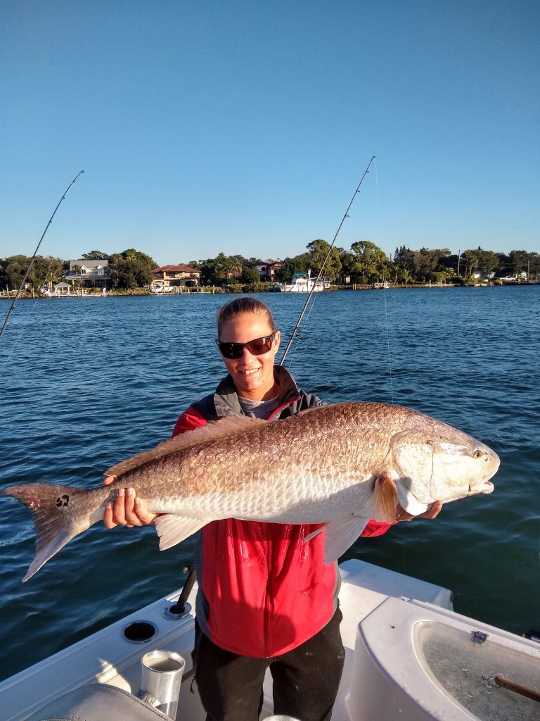 a guy holding a redfish on a boat in new smyrna beach, fl