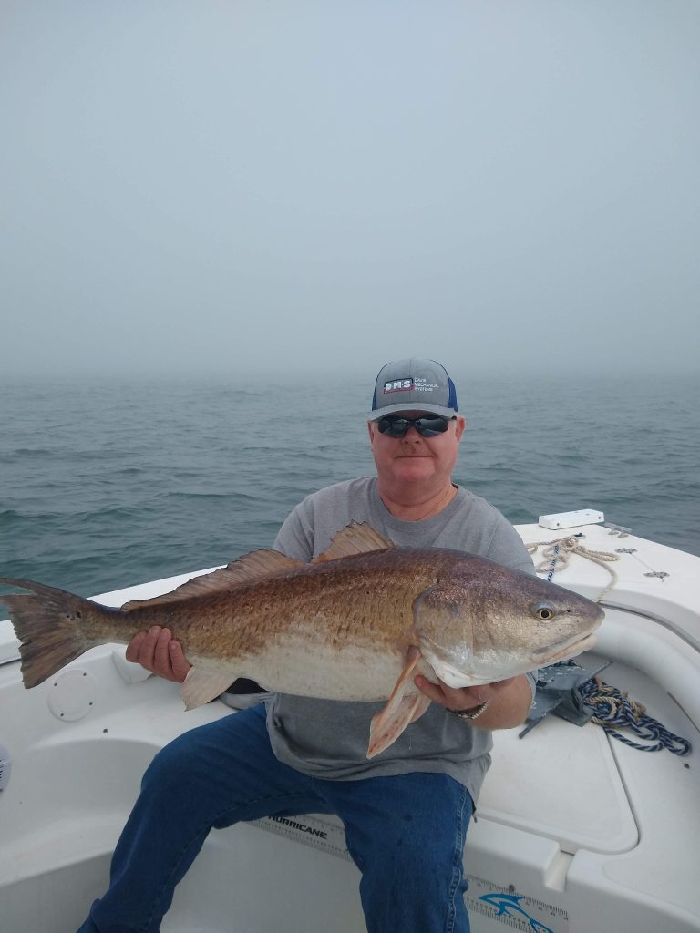 a guy holding a redfish on a boat in new smyrna beach, fl