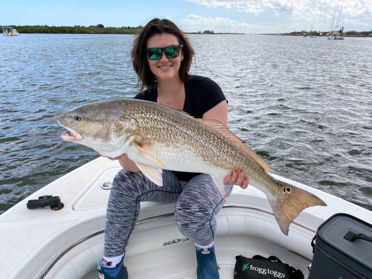 a girl holding a redfish on a boat in new smyrna beach, fl