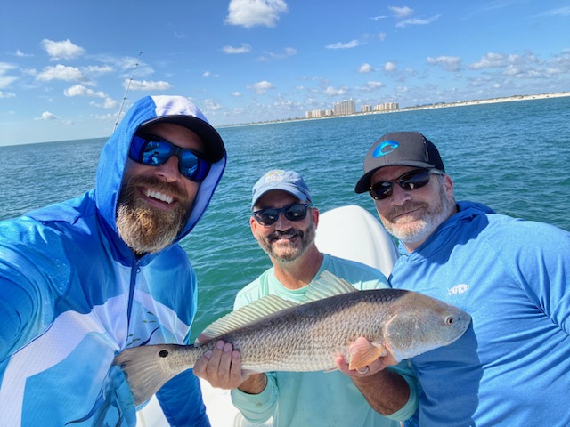 captain eric and two guys holding a redfish on a boat in new smyrna beach, fl