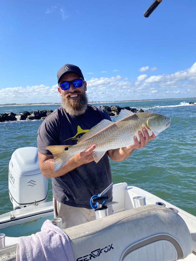 captain eric holding a redfish on a boat in new smyrna beach, fl