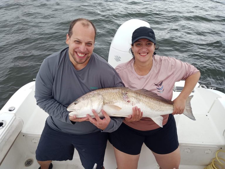 a couple posing with a redfish on a seafox boat